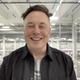 Elon Musk smiling in front of the floor of one of his battery factories.